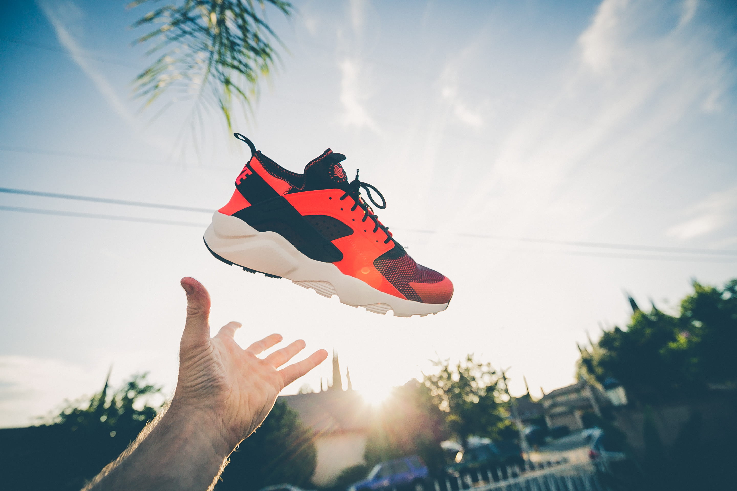 unpaired orange and white Nike Air Huarache, person throwing orange and white shoe