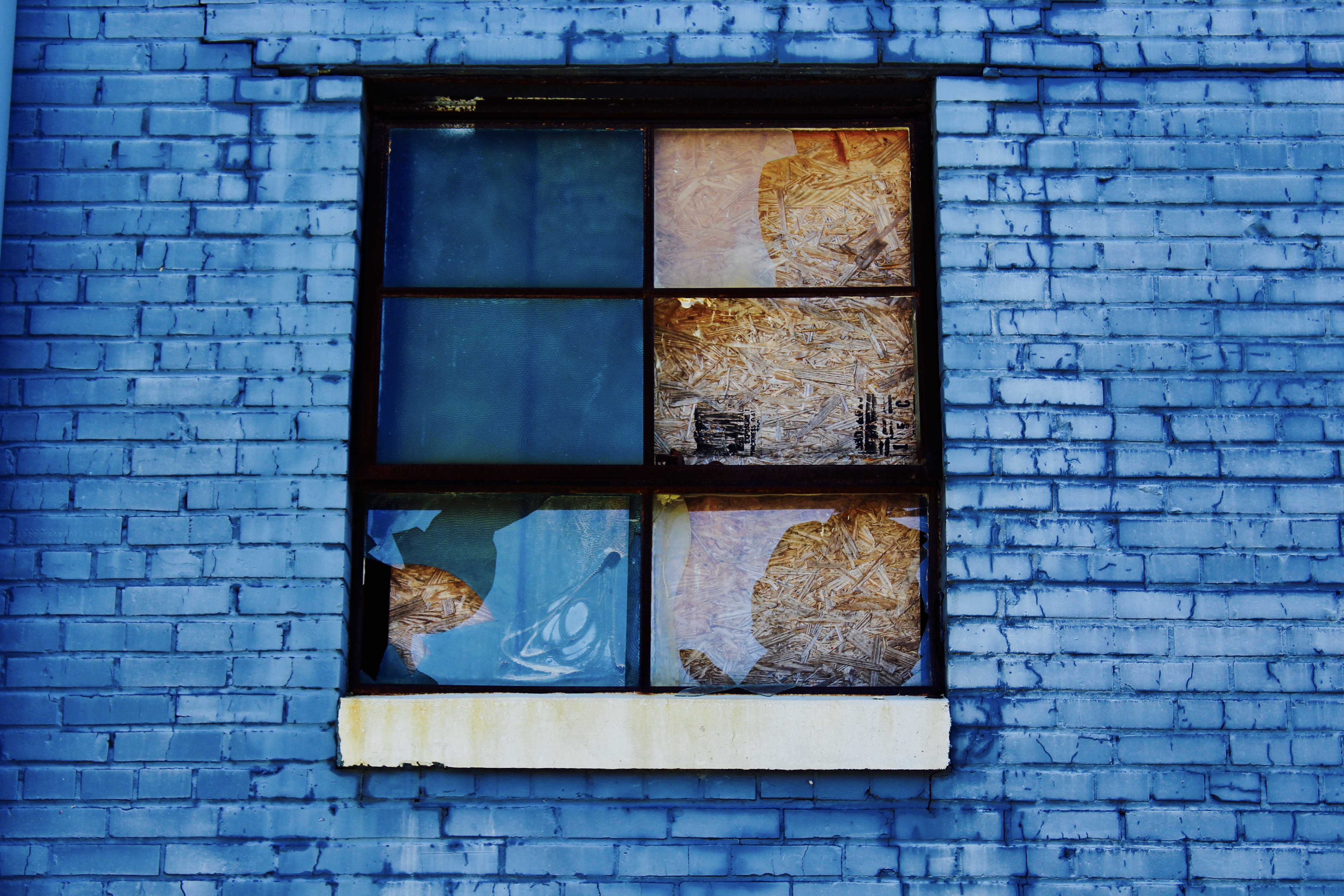 Broken Window, black sash window on blue brick building, wall