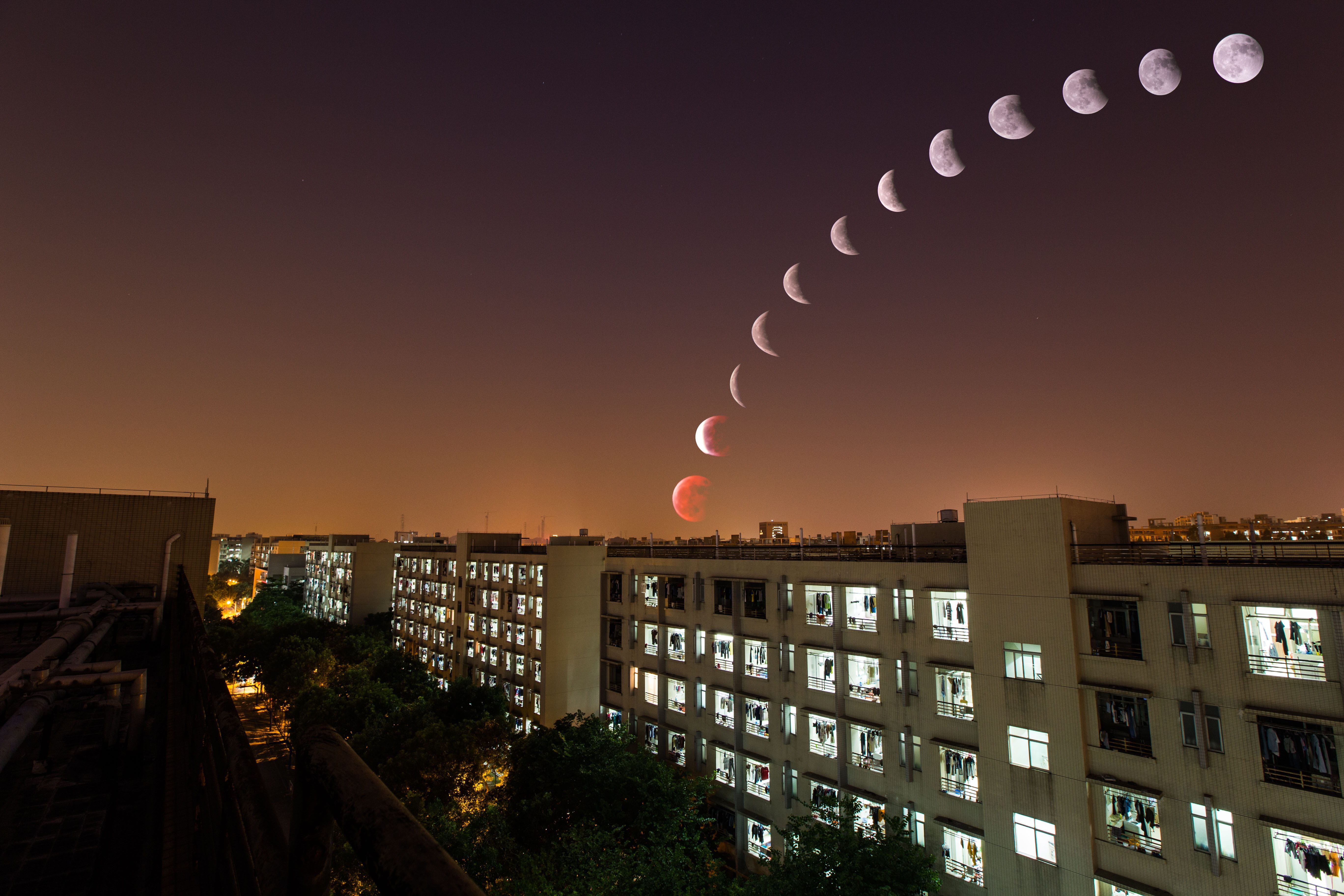 white concrete building under moon at nighttime, lunar eclipse