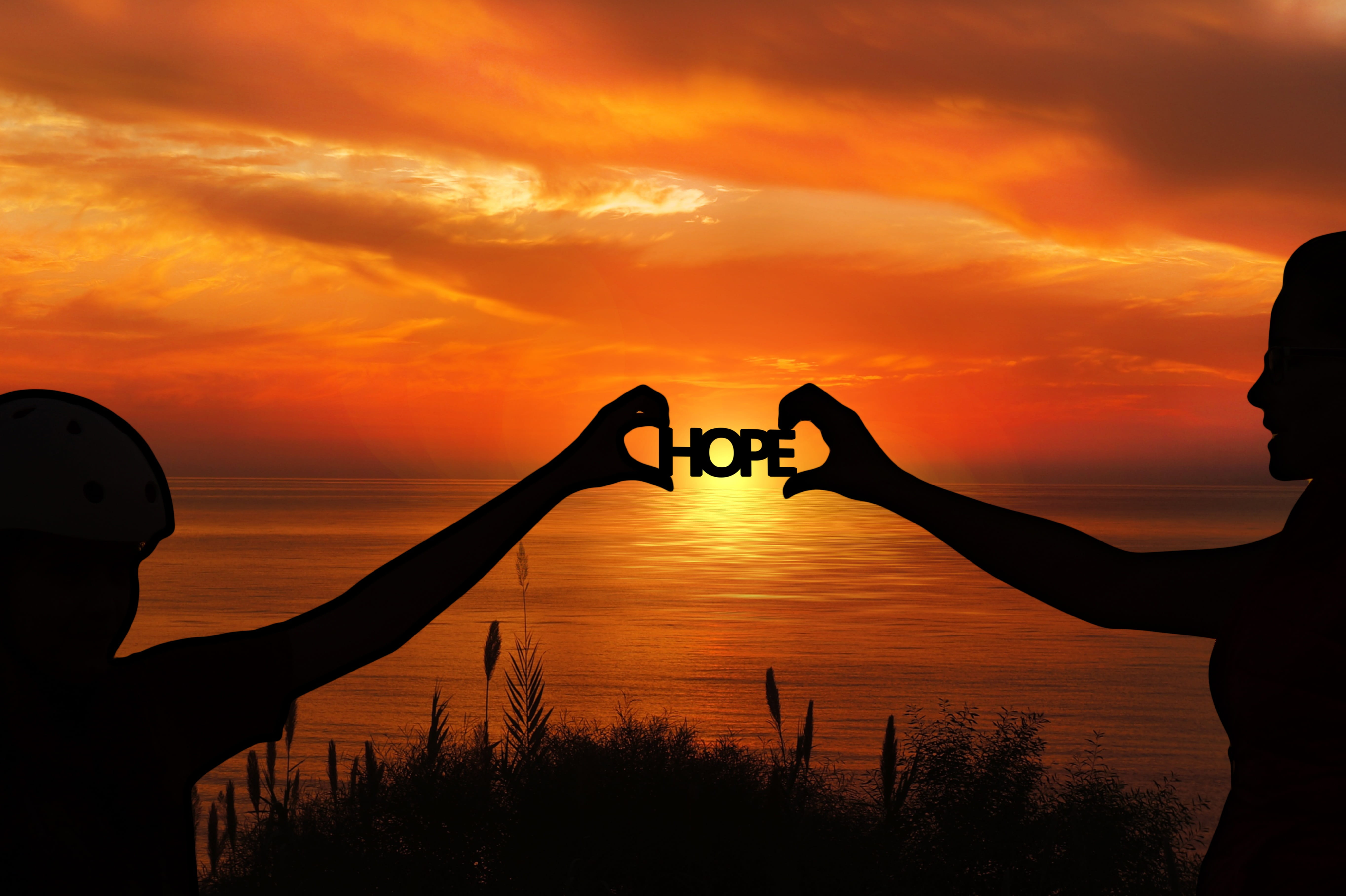 silhouette of people holding HOPE logo during sunset, forward
