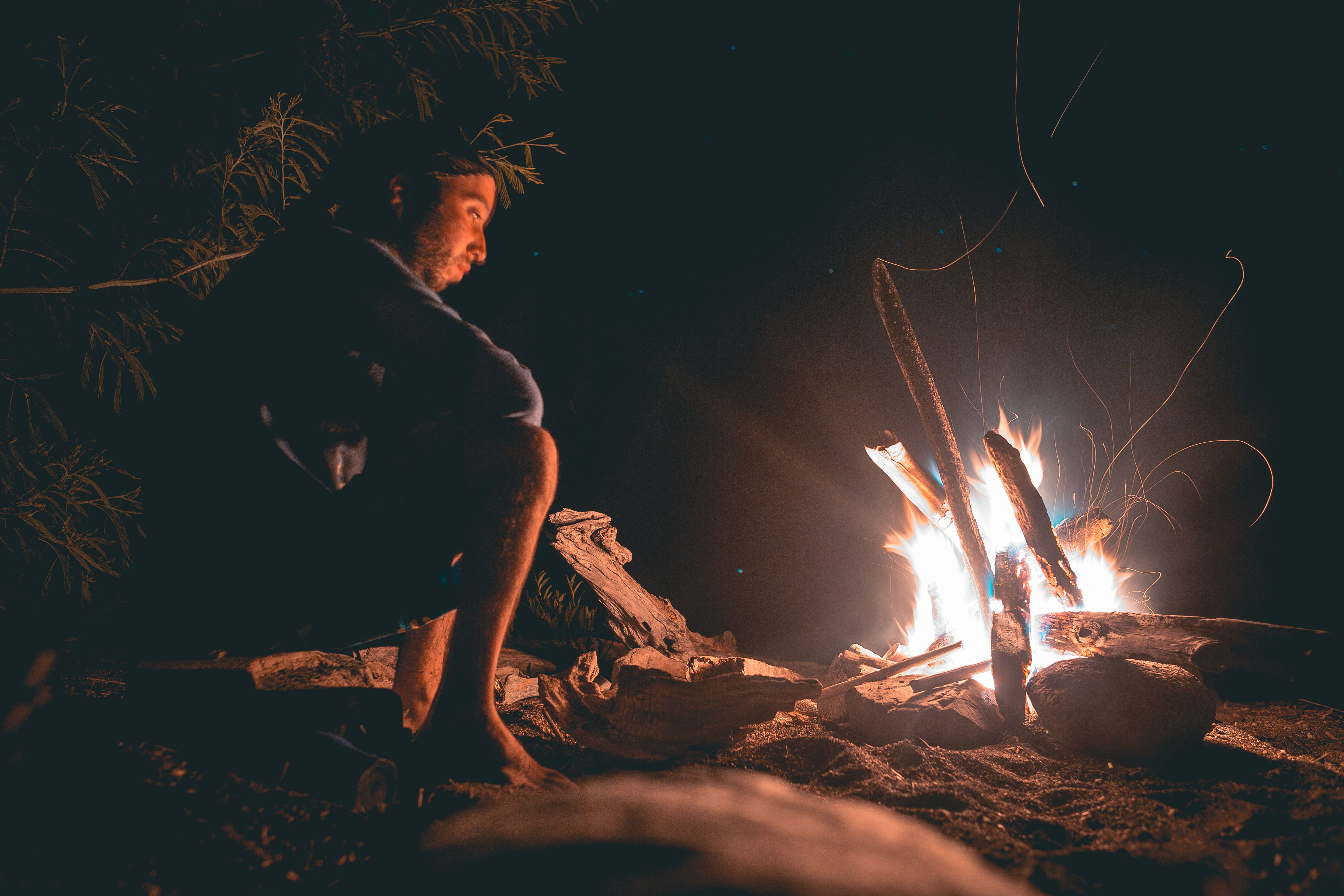 man seating beside fire, man sits near fire, camp, campfire, glow