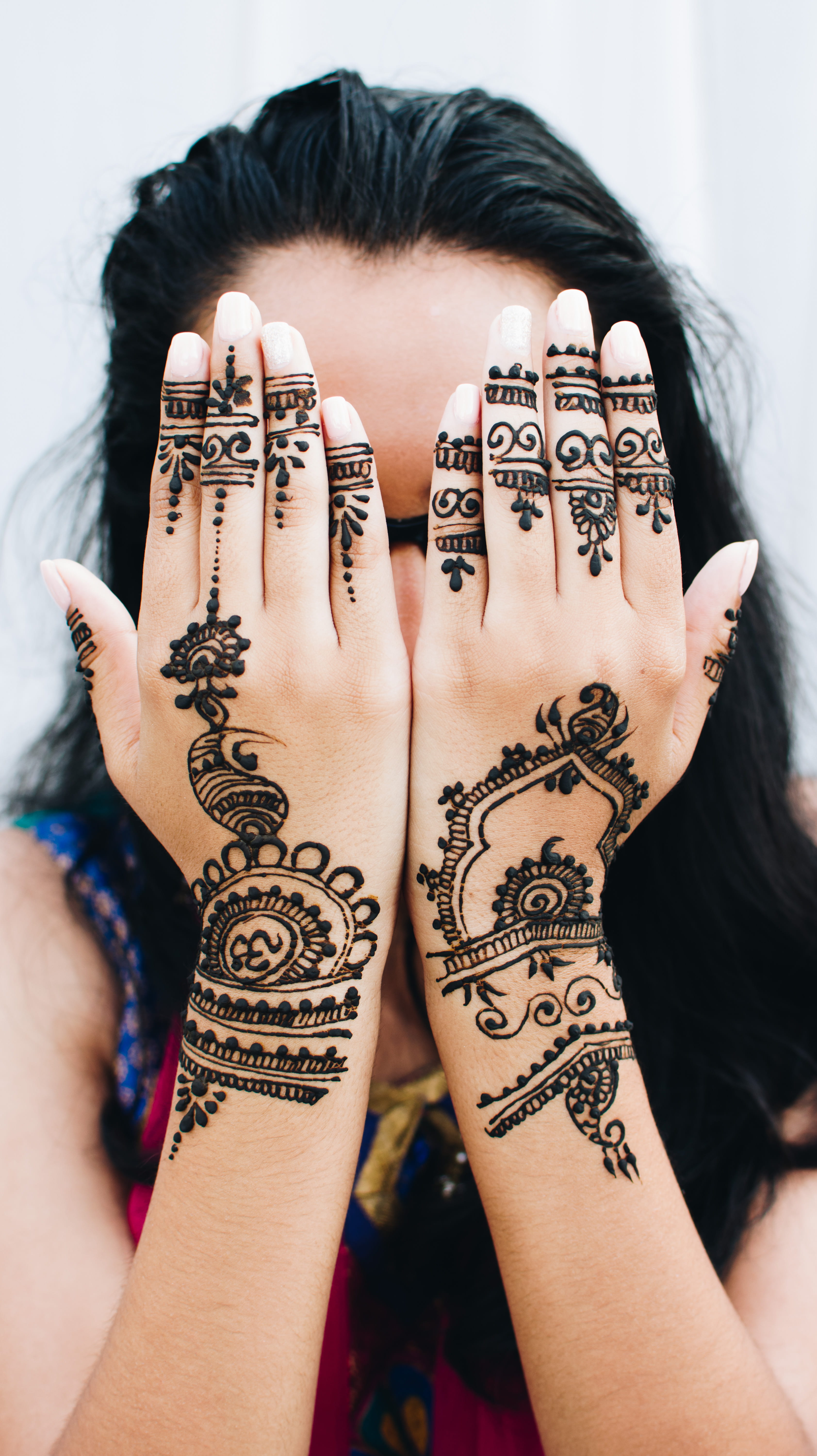 woman covering her face with her two hands, woman showing mehndi tattoo