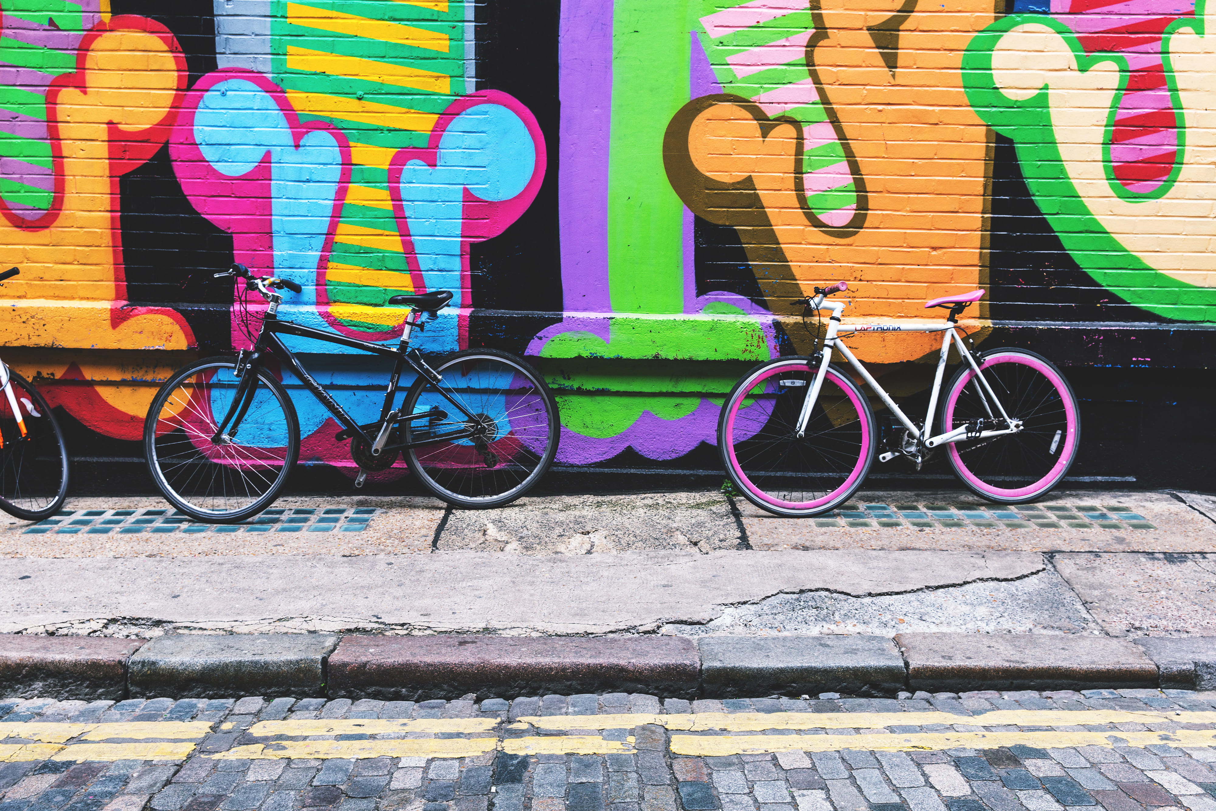 Bicycles stand against a street-art covered wall in the city