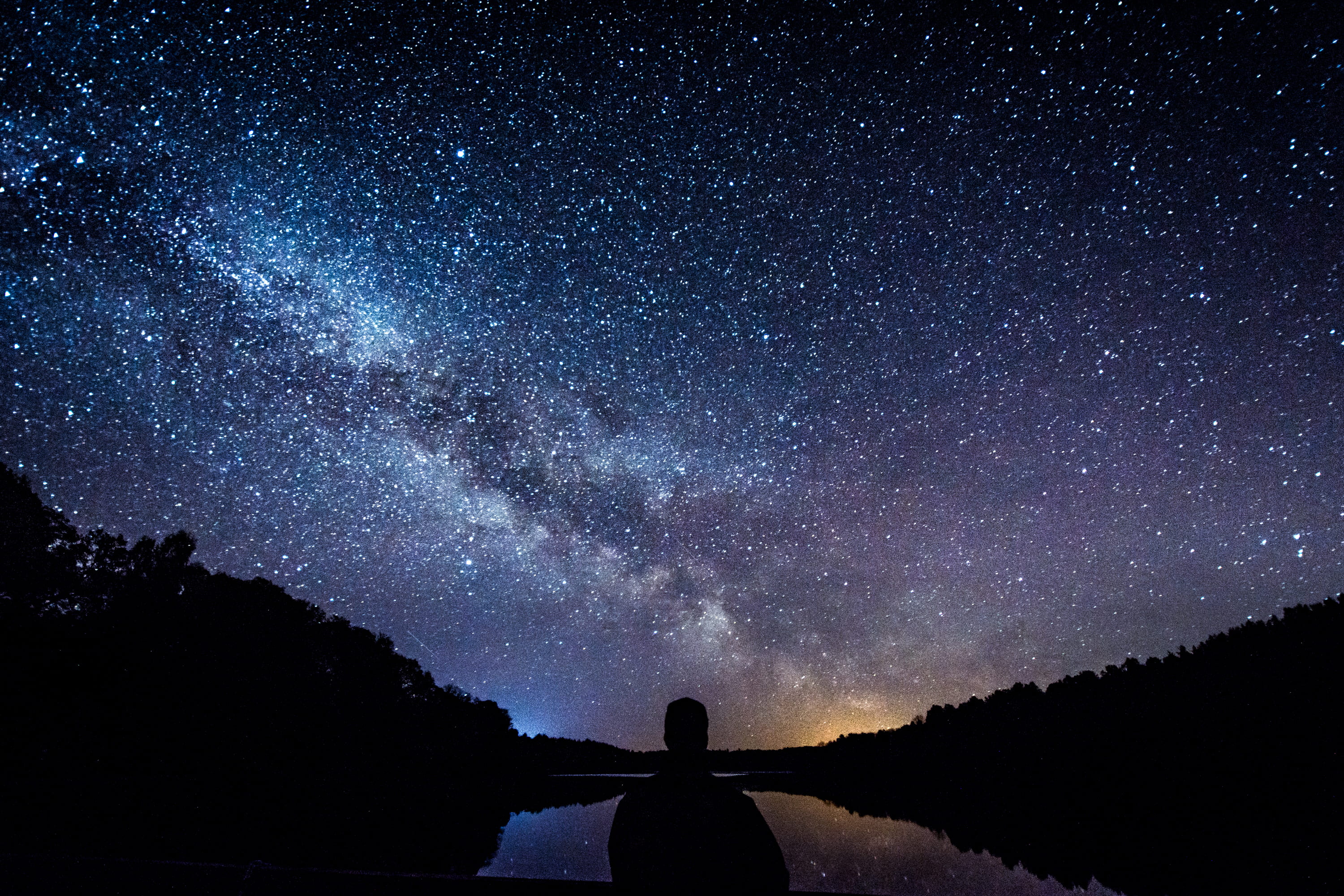 silhouette of person standing under starry sky, silhouette of person near body of water under starry night