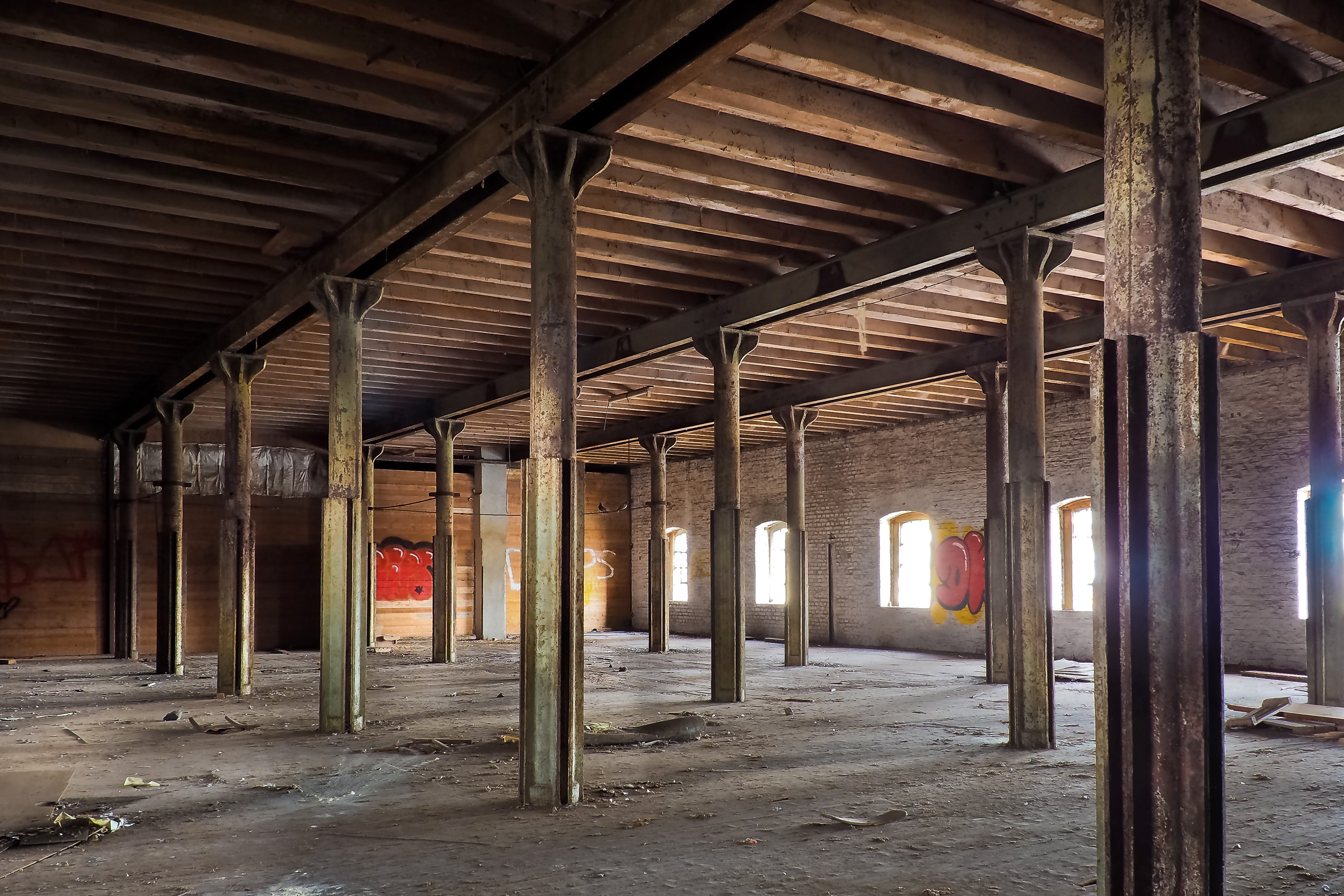 empty warehouse with rusted metal posts, brown house, lost places