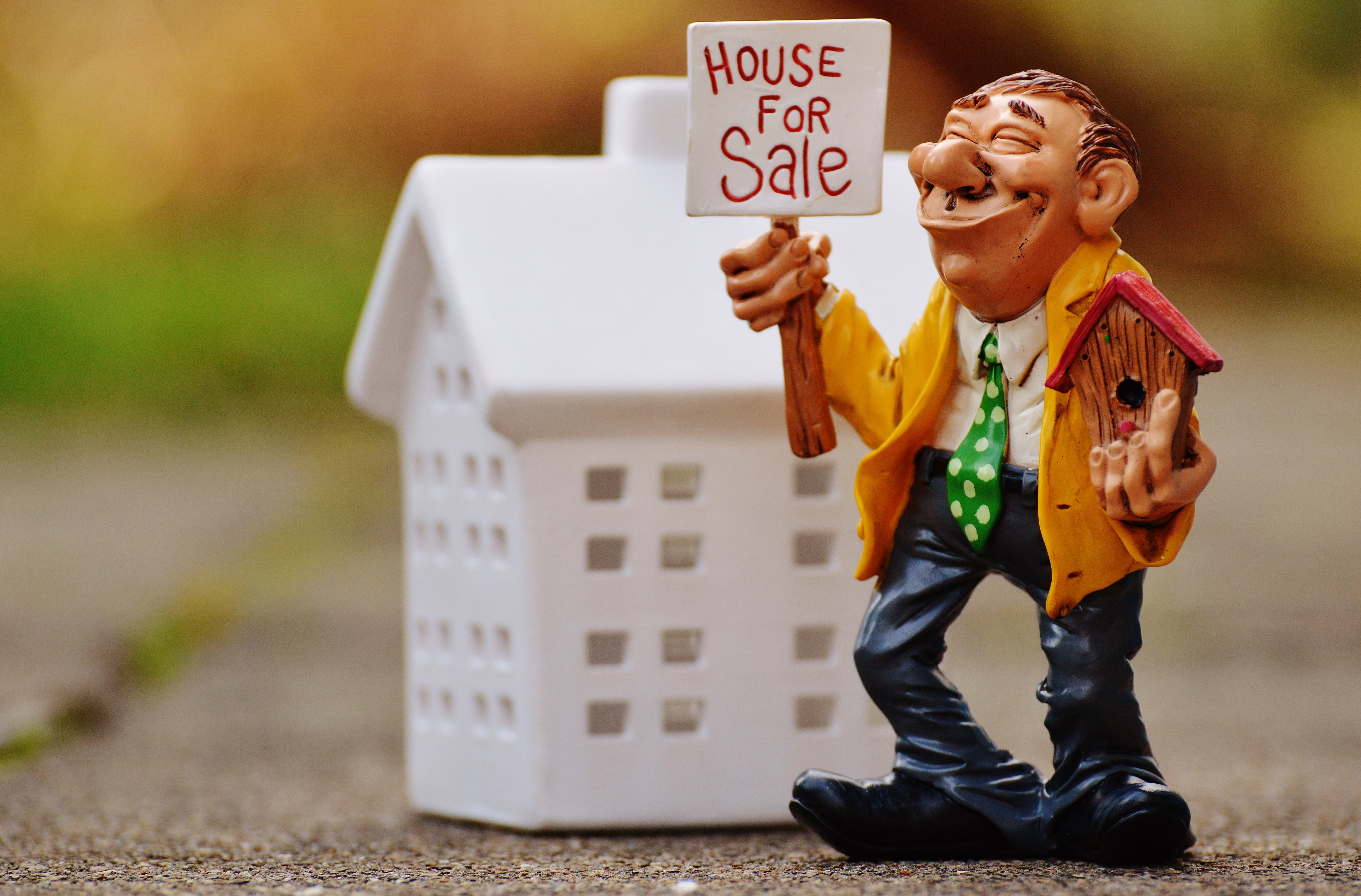 ceramic man holding house for sale figurine, real estate agents