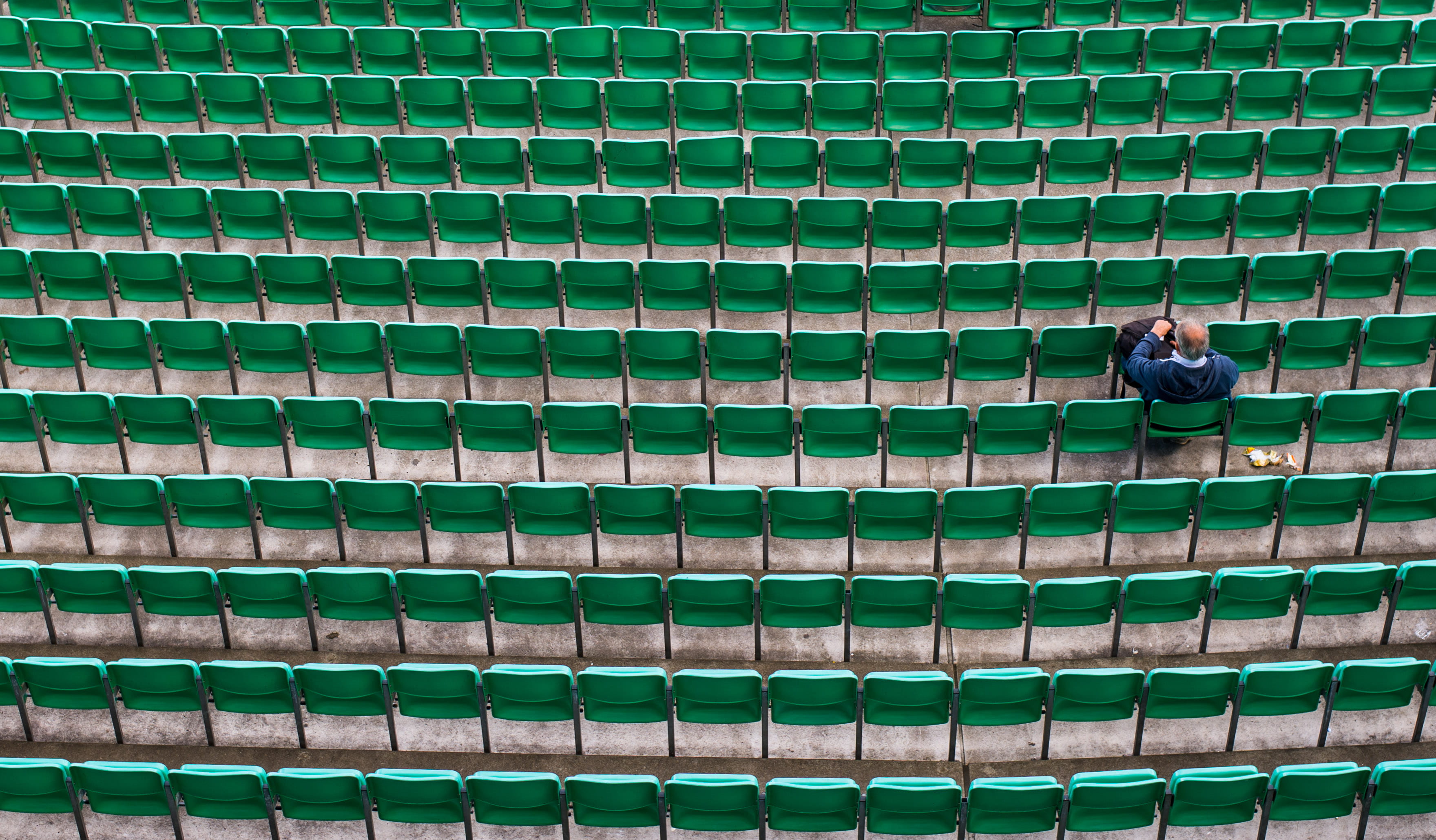 man sitting on bleachers, person sitting on green chairs, seats