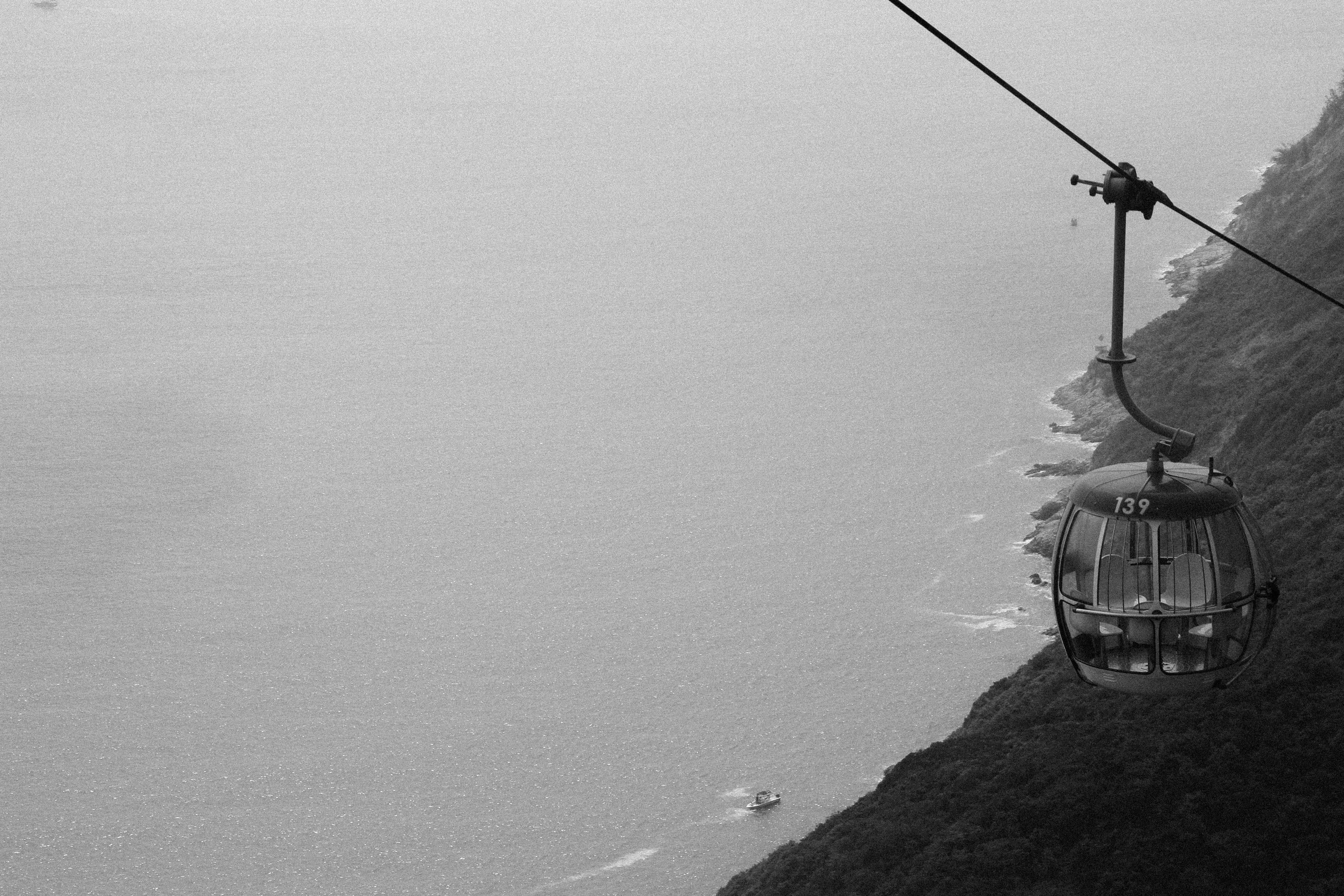 grayscale photography of cable car distance with sea, grayscale photo of cable car near body of water