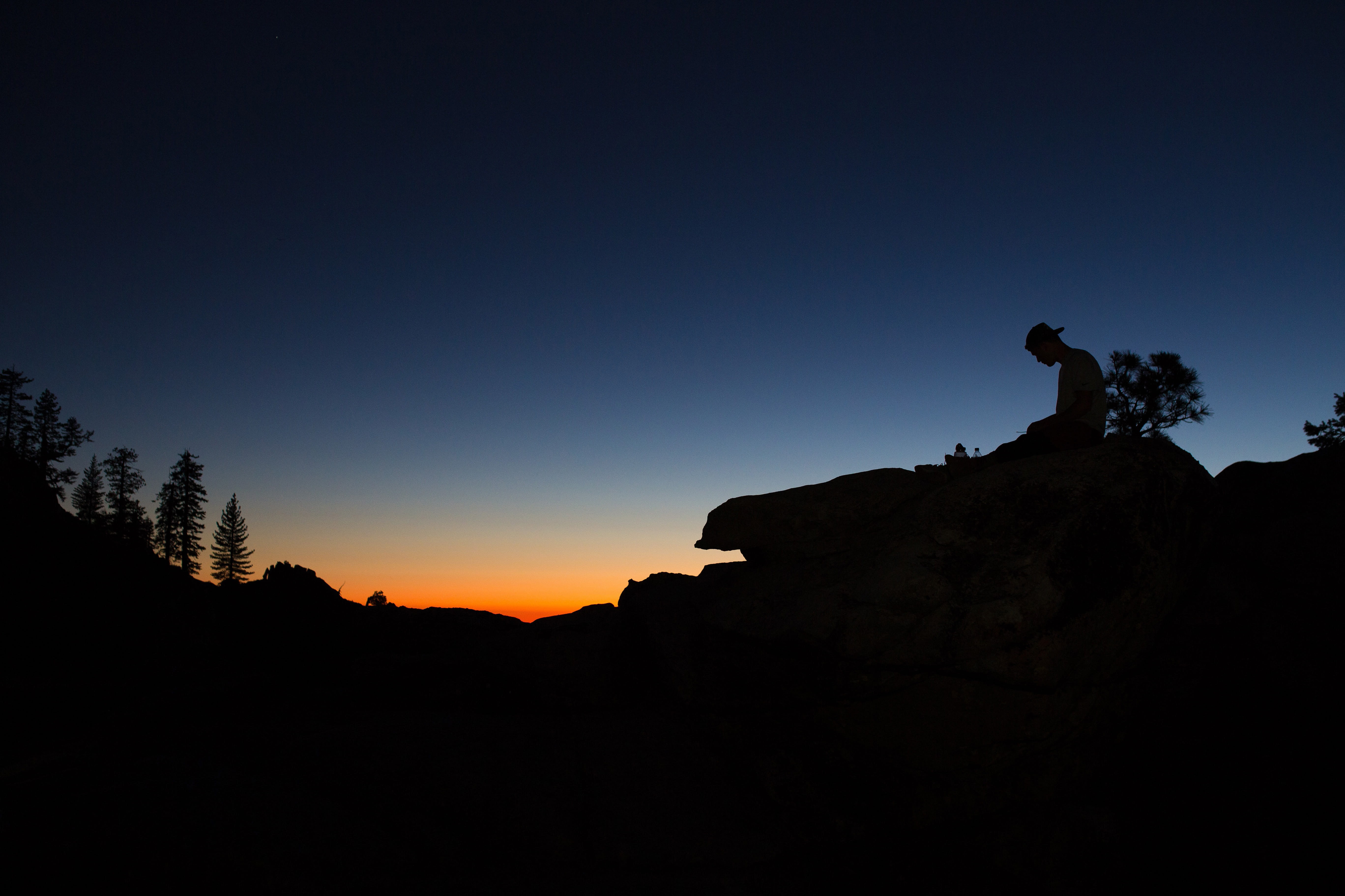 Silhouette of a man sitting on a rock at sunset in Yosemite Valley, USA