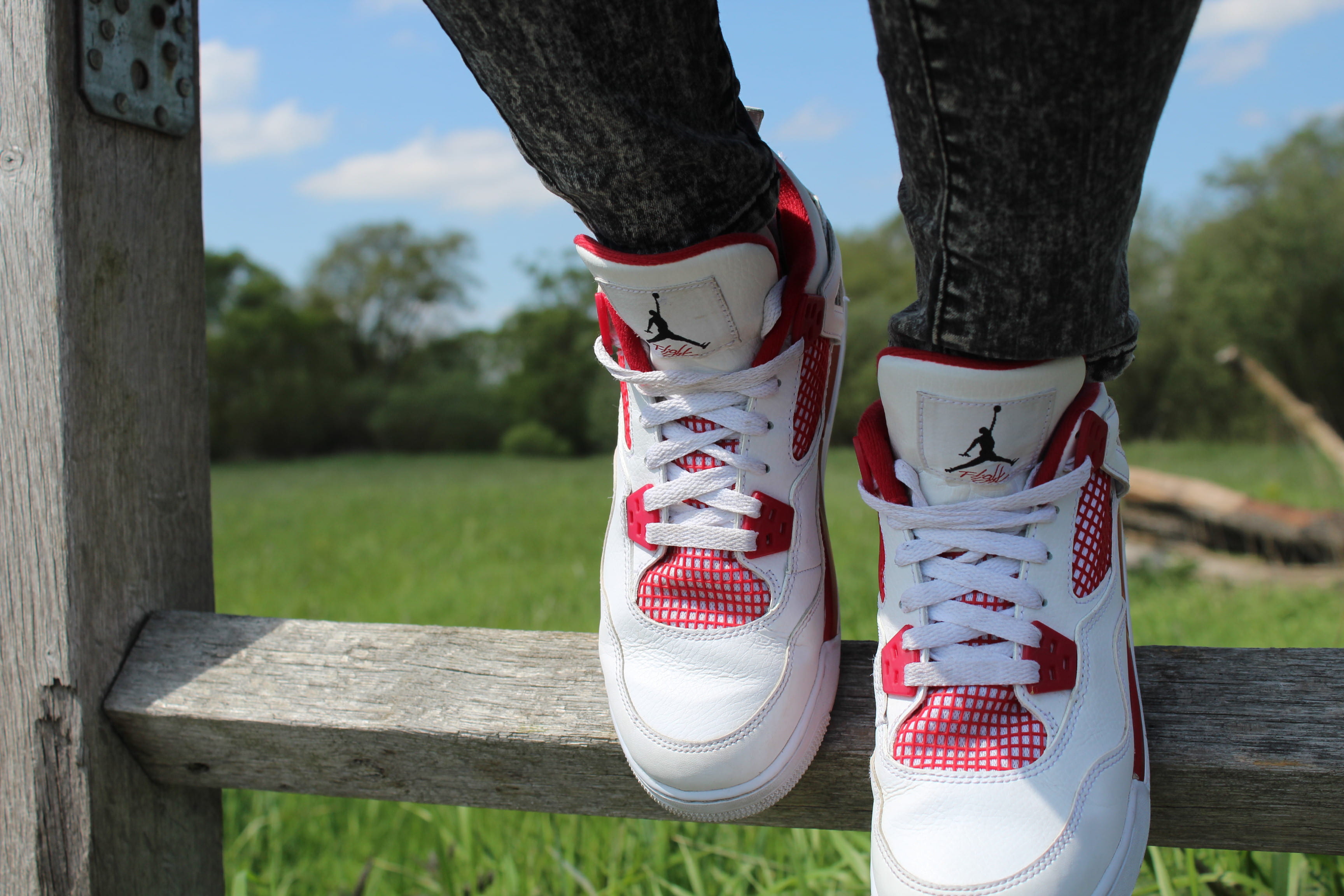 person wearing pair of red-and-white Air Jordan shoes, person wearing white-and-red Air Jordan Flight shoes