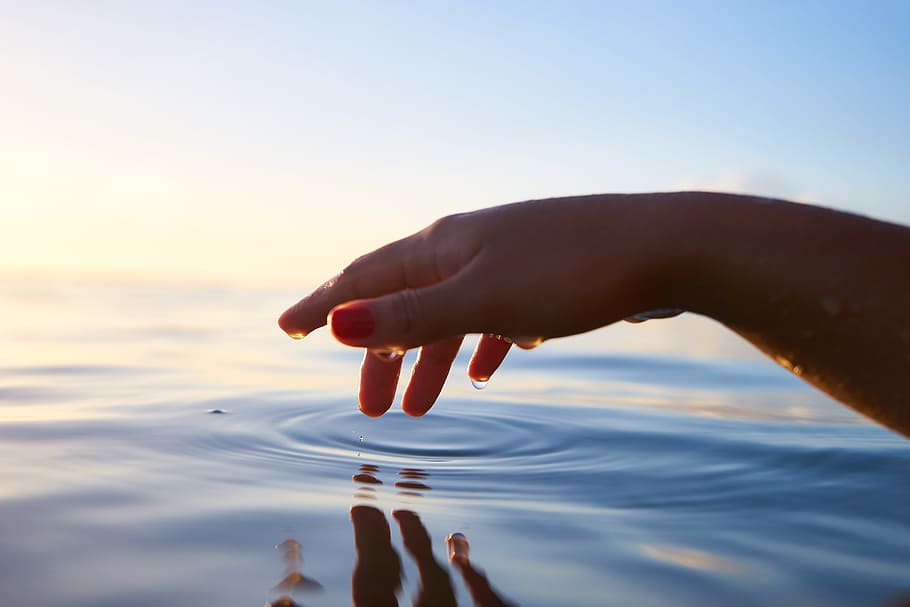person about to touch the calm water, person's right hand on top of the water timelapse photography HD wallpaper