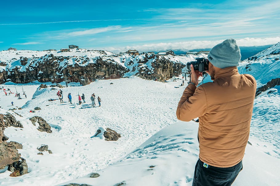 man standing on glacier mountain taking photo, man taking photo on snow covered field HD wallpaper