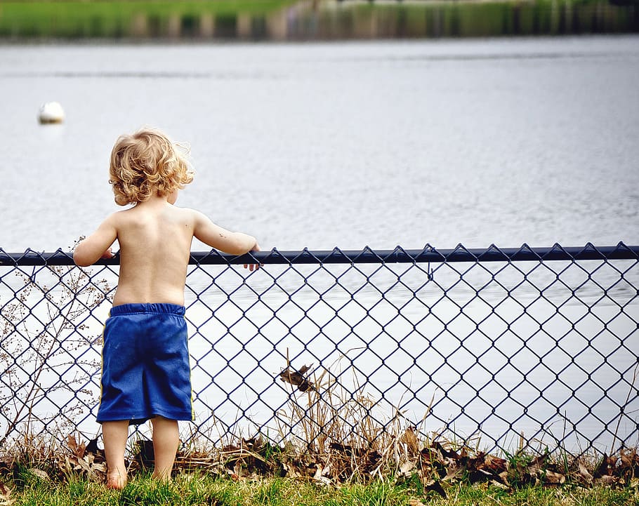 boy leaning on gray metal fence beside lake, kid, young, water HD wallpaper