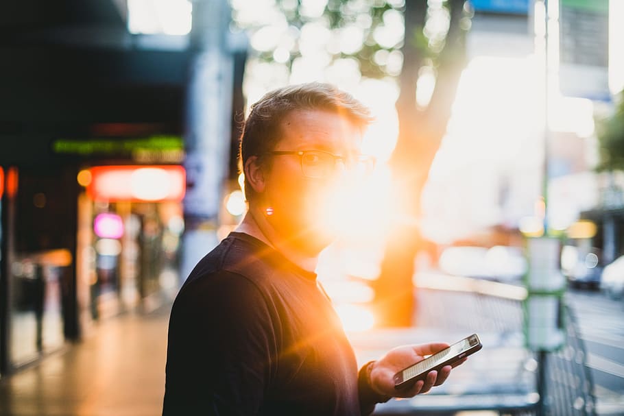 man standing on street, man standing beside tree while holding phone HD wallpaper
