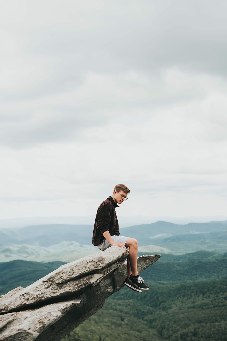 man sitting on the edge of stone, man sitting on mountain cliff