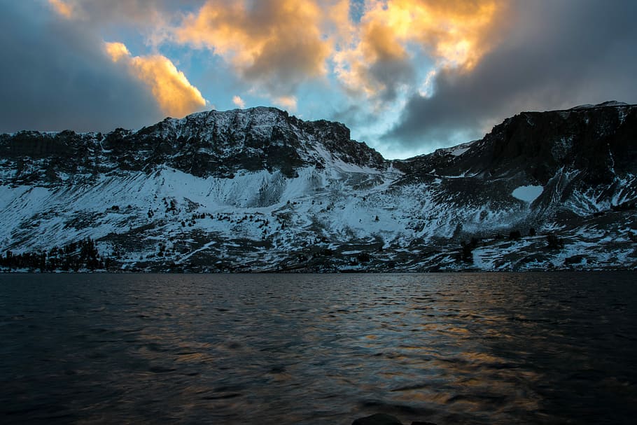 gray mountain covered by snow beside body of water, rocky mountain during sun rise HD wallpaper