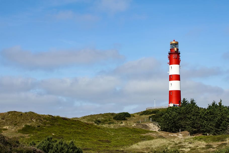 lighthouse beside trees with cloudy sky, dune, amrum, north sea