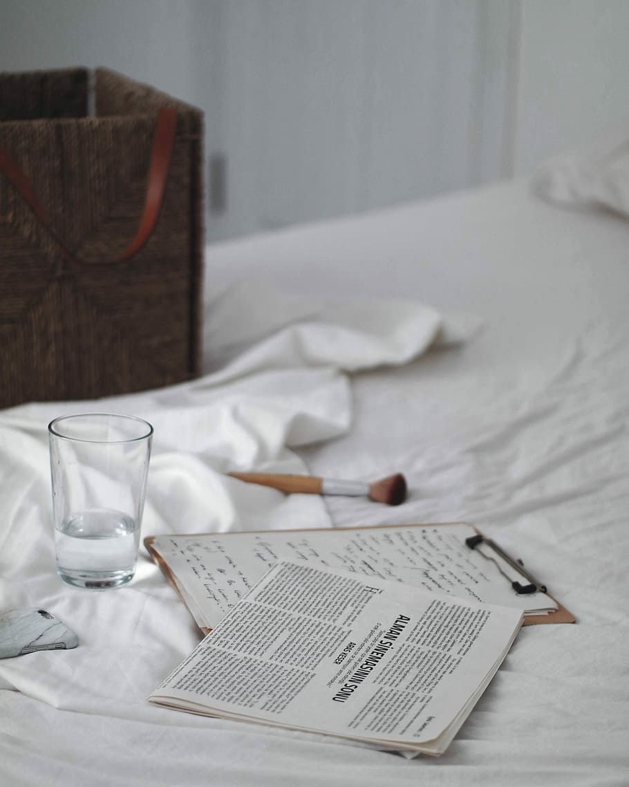 drinking glass beside clipboard on bed, clear shot glass beside brown clipboard HD wallpaper
