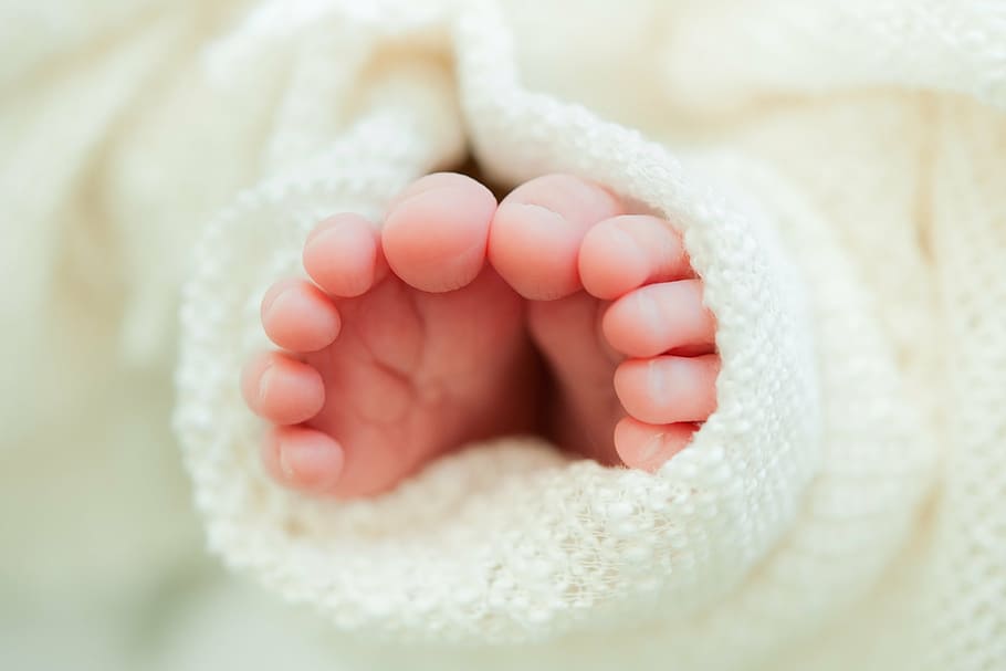 baby's feet on white textile, newborn toes, white blanket, close up