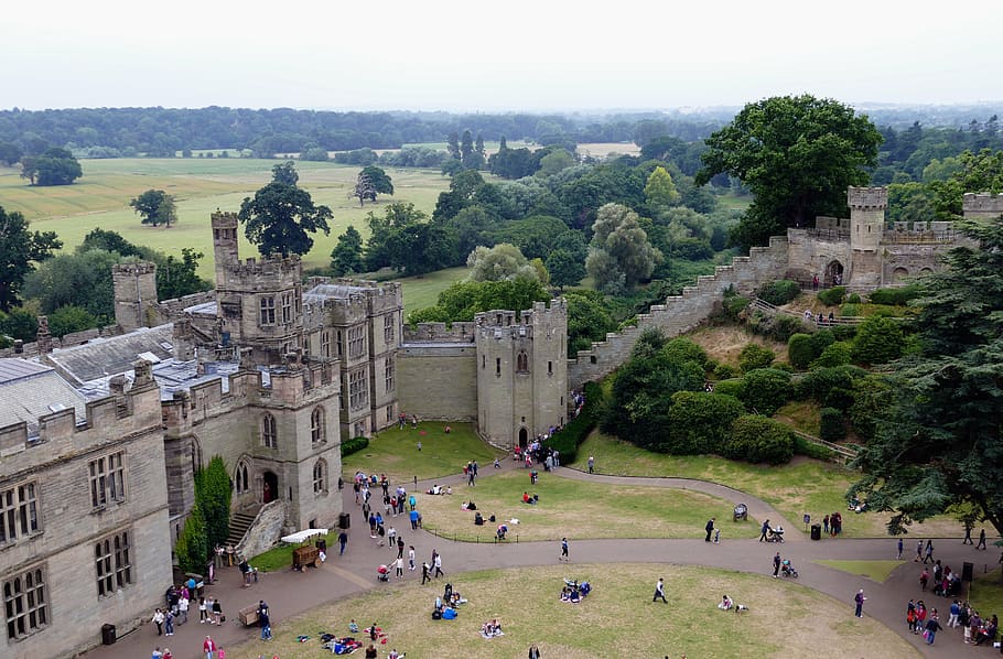 aerial photography of people standing and sitting near grey concrete castle during daytime