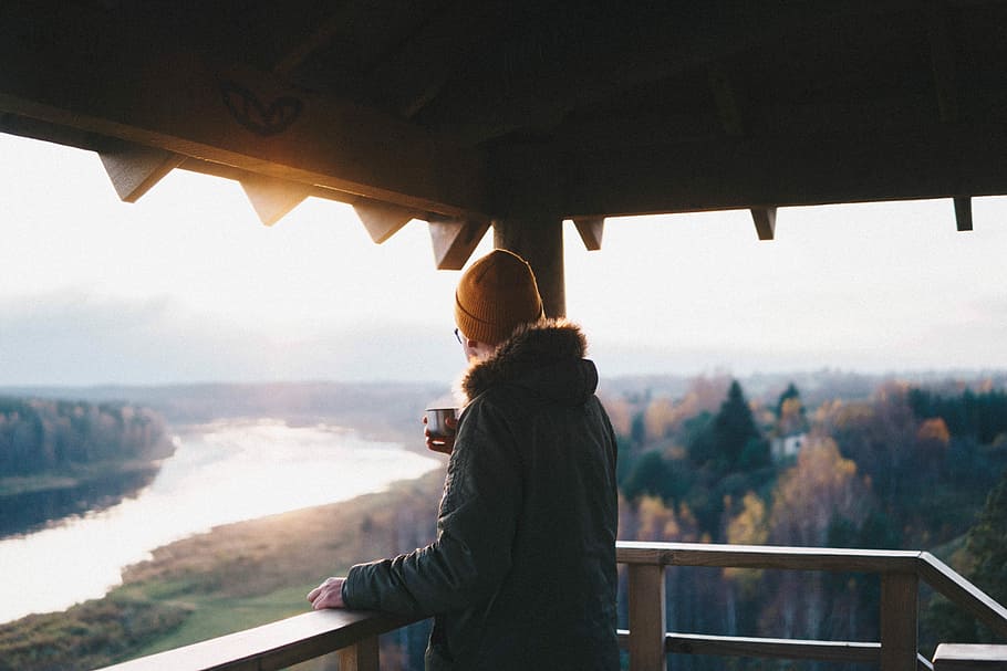 man holding ceramic cup while standing, person standing on balcony holding cup of coffee HD wallpaper