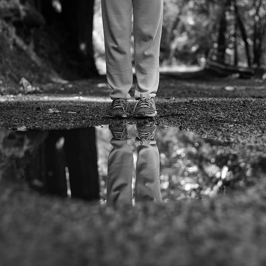 grayscale photo of man standing in front of water on ground HD wallpaper
