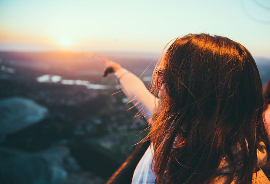 selective focus photography of woman pointing on sky, woman pointing to the sun during sun set HD wallpaper