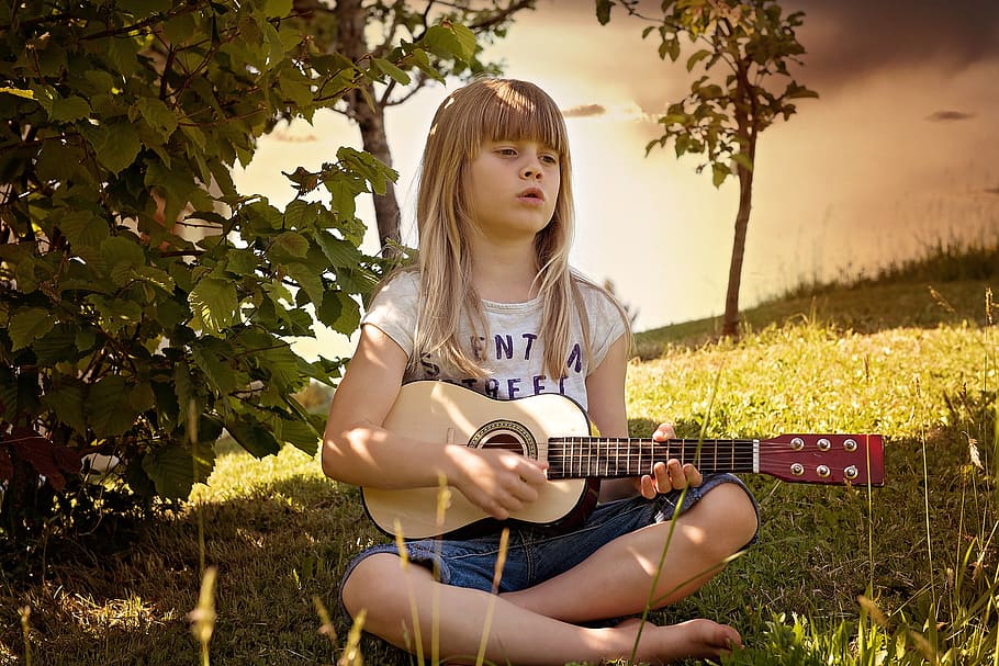 girl playing ukulele on grass field, person, human, child, guitar