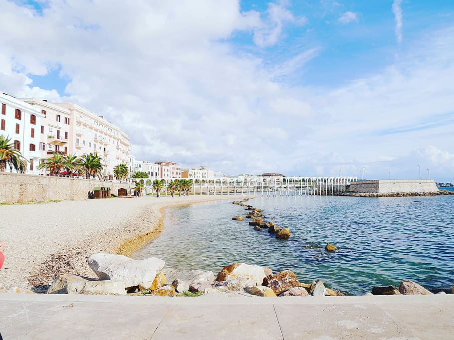 white concrete building near body of water under white and blue sky, buildings neat the bay and dock during day HD wallpaper