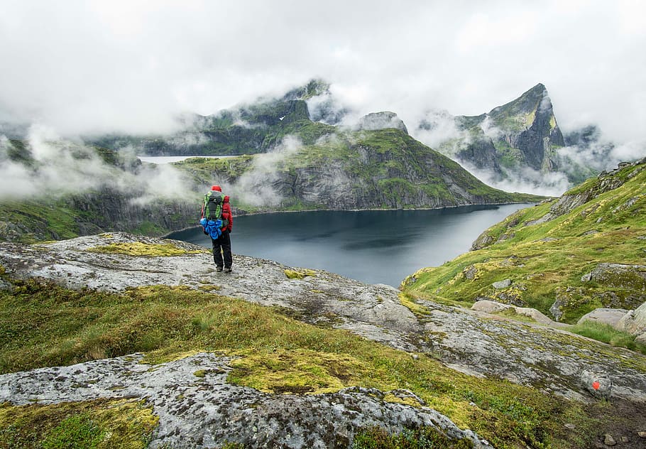 person standing on top of mountain during daytime, man standing on stone staring at body of water HD wallpaper