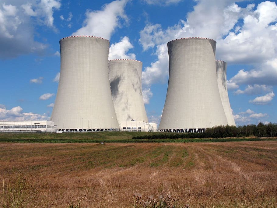 white power plant surrounded by green field, chimney, concrete
