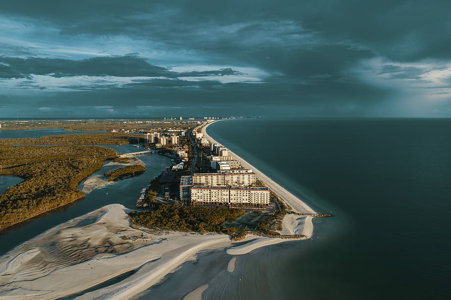 aerial photography of white house beside ocean under gray clouds at daytime, dark clouds over building HD wallpaper