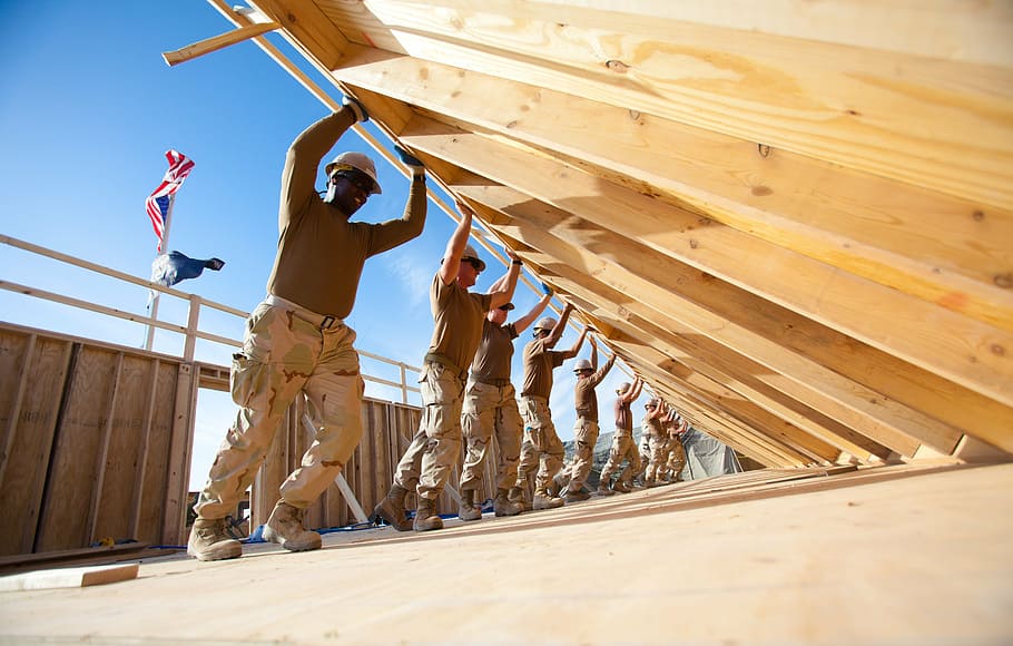 group of men pushing beige wooden wall during daytime, teamwork HD wallpaper