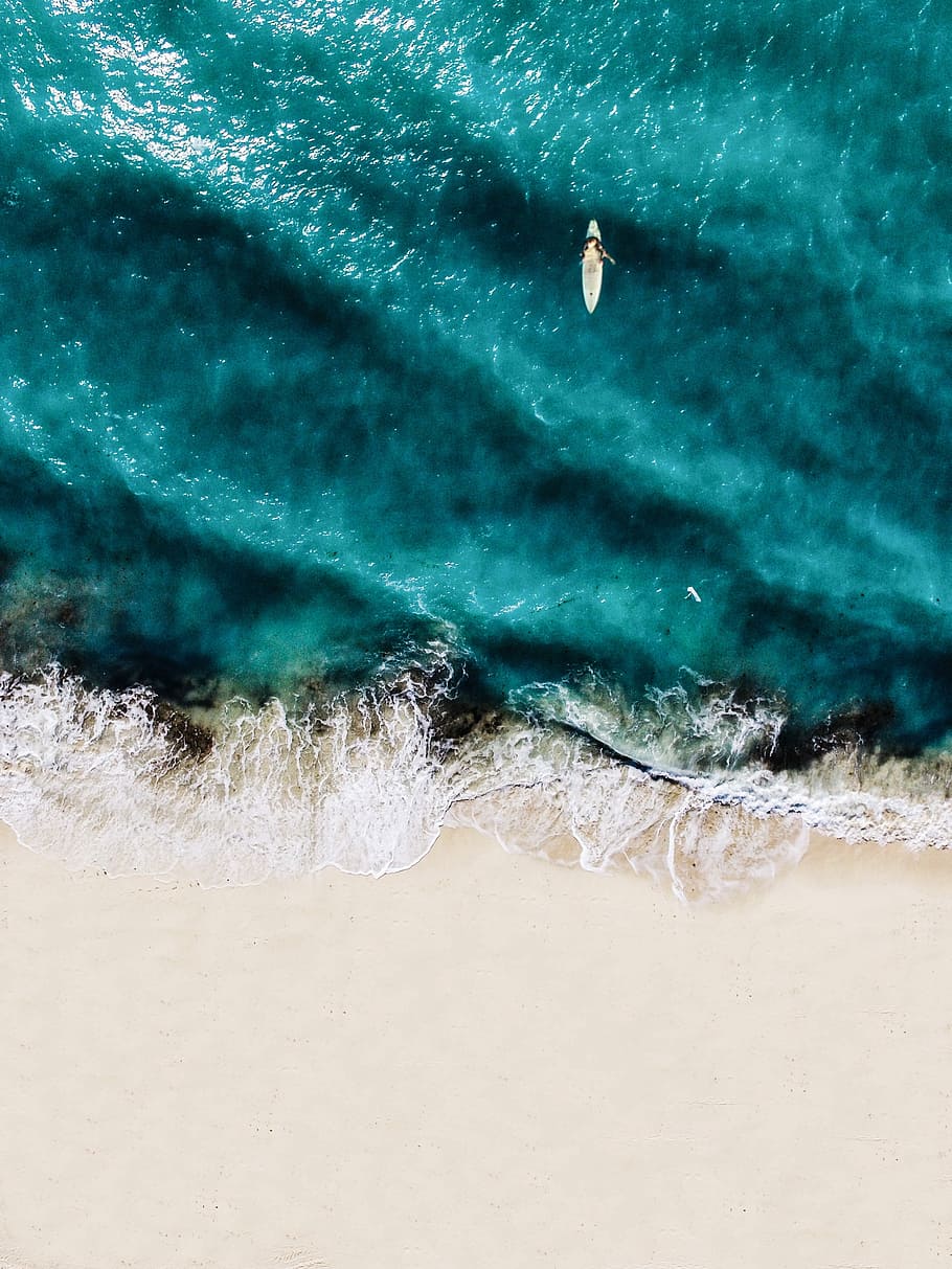 beach from above, aerial photo of person riding surfboard on bodies of water