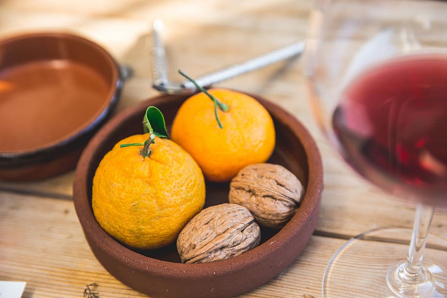 two oranges and two nuts on round brown clay bowl, bowl of orange fruits and walnuts HD wallpaper