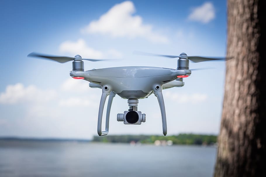 selective focus photography of white drone flying beside tree trunk HD wallpaper