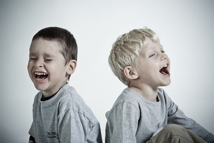 photography of two children wearing heather gray shirts while laughing