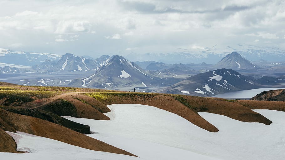 shallow focus photography of brown and white mountain, person standing on pathway near mountain HD wallpaper