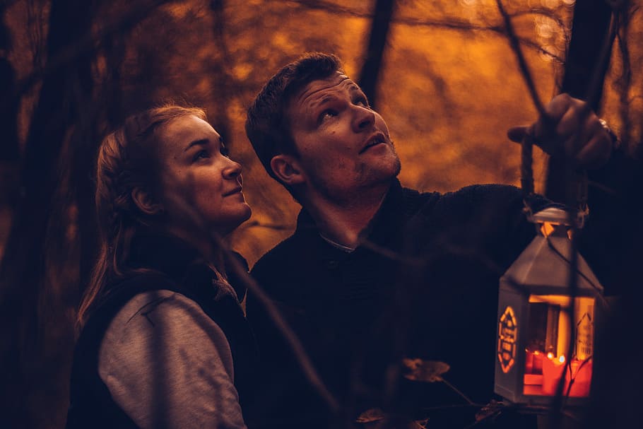 man carrying candle lantern beside woman both looking at top, man and woman looking upwards HD wallpaper