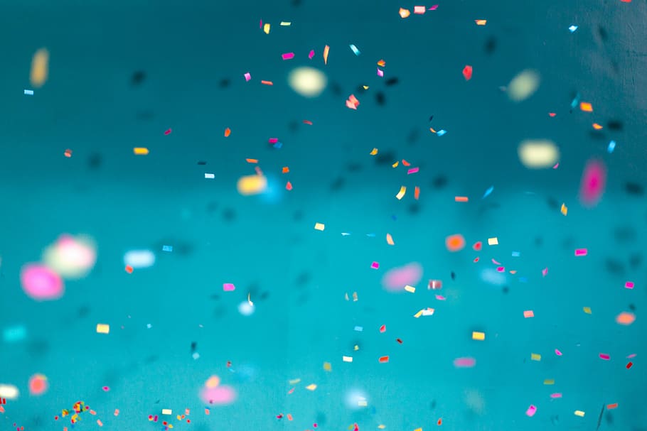 selective focus photography of multicolored confetti lot, confetti floating over blue surface