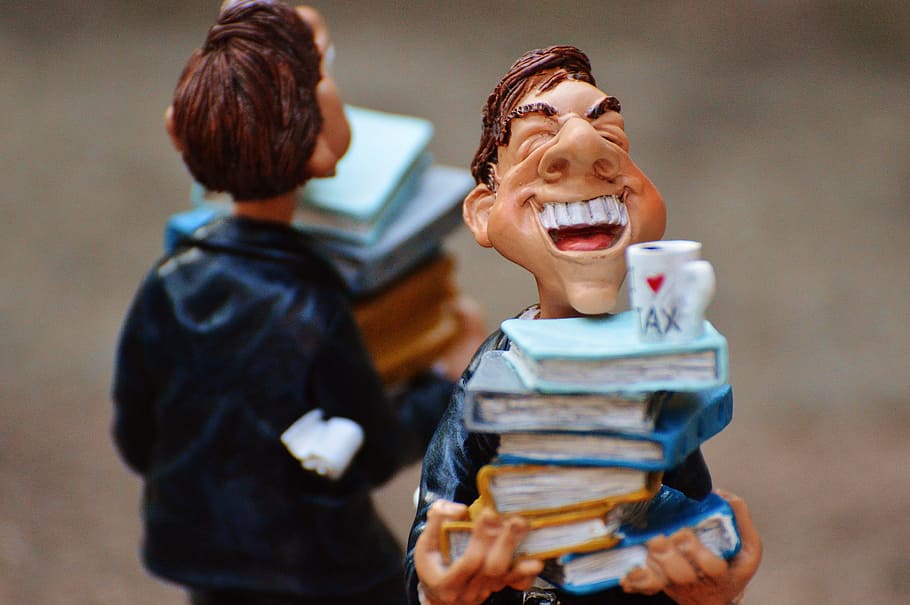 selective focus photography of man carrying pile of books figurine