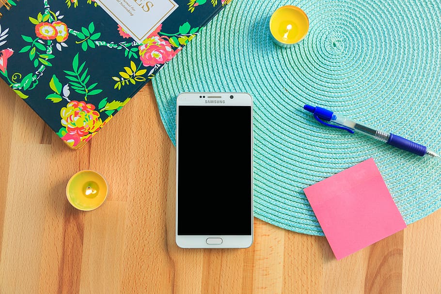 white Samsung Galaxy smartphone on top of blue place mat near blue click pen, white Samsung smartphone on wooden surface HD wallpaper