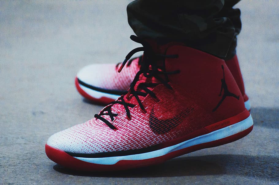 person wearing pair of red-and-white Air Jordan basketball shoes, man wearing pair of red-white-and-black Air Jordan 31's