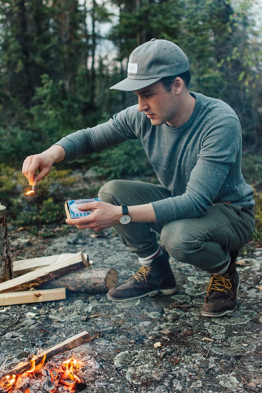 selective focus photography of man holding lit matchstick outdoors, man ducking while holding safety match HD wallpaper
