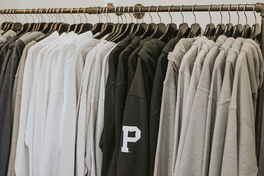 closeup of hanged hoodies, gray, black, and white hoodies hanged on rack