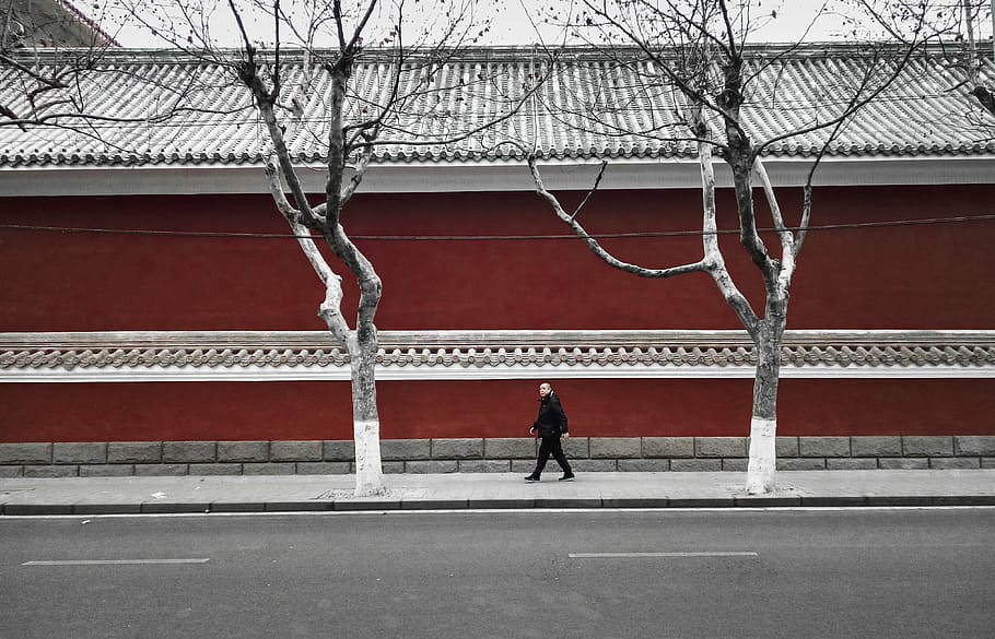 man walking on pathway near wall, man walking on pathway near red building HD wallpaper