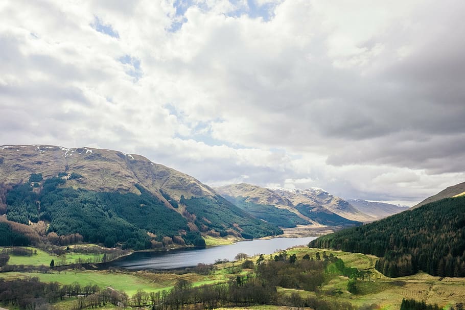 body of water in between mountains under white clouds at daytime HD wallpaper