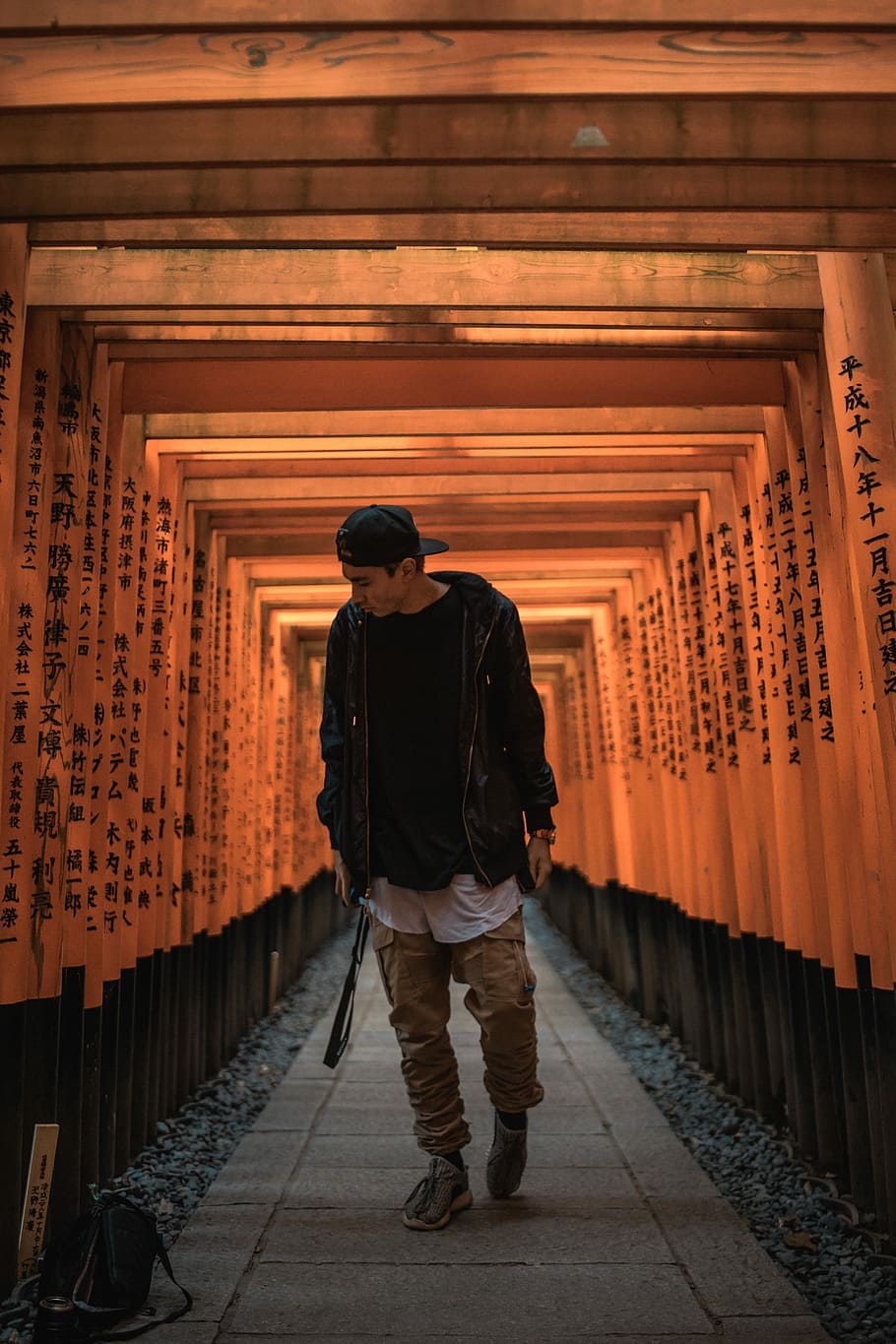 man standing between torii gate, man walking between wooden arc