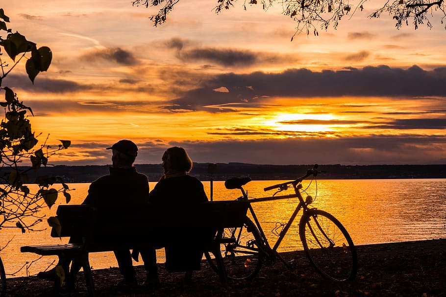silhouette of man and woman sitting on bench facing body of water, HD wallpaper