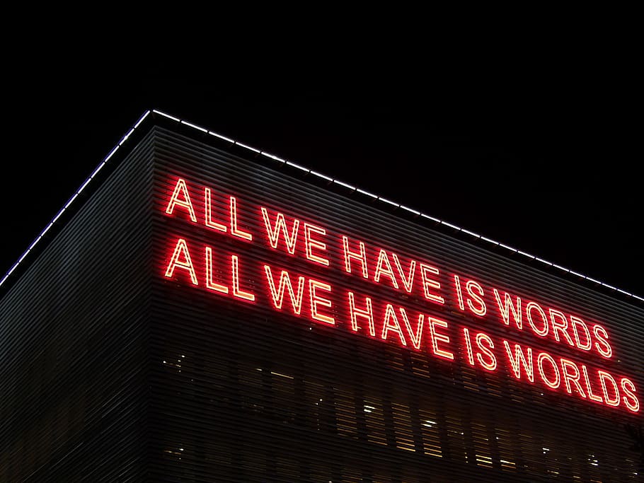 All We Have Is Words All We Have Is Worlds lighted signage at night, high rise building